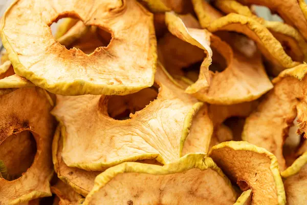 Kurutulmuş elma dilimlerine yakın çekim. Sağlıklı atıştırmalıklar ve tarifler için ideal. Çekici bir mutfak sunumu için susuz kalmış meyvenin dokusunu, rengini ve besin faydalarını gösterir.