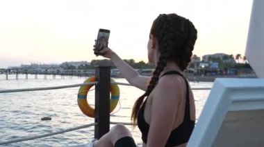 Bir kız iskelede güneşlenir ve selfie çeker. Yüksek kalite 4k görüntü