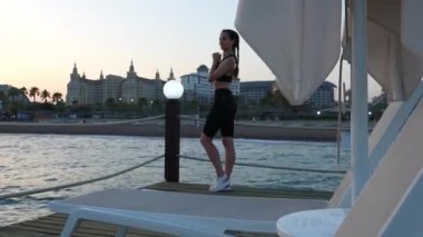 Spor giyimli bir kız Akdeniz 'de bir rıhtımda yürüyor. Yüksek kalite 4k görüntü