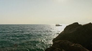 Gün batımında kayalık sahil ve deniz manzarası. Antalya. Tekne denizde yüzüyor. Yüksek kalite 4k görüntü