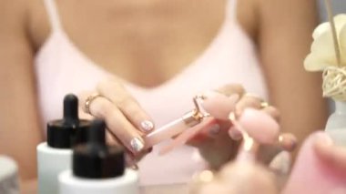 Kız, Gua Sha ve Roller 'ı aynanın önünde yüz bakımı için kullanıyor. Yüksek kalite 4k görüntü