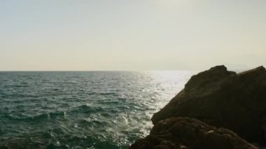 Gün batımında kayalık sahil ve deniz manzarası. Antalya. Tekne denizde yüzüyor. Yüksek kalite 4k görüntü