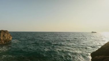 Gün batımında kayalık sahil ve deniz manzarası. Antalya. Tekne denizde yüzüyor. Yüksek kalite 4k görüntü