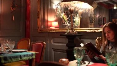 Eski bir kafede romantik bir ortamda kitap okuyan bir kız. Yüksek kalite 4k görüntü