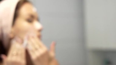 Aynanın yanında yüzüne yüz temizleyici süren bir kadın. Yüksek kalite 4k görüntü