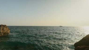 Gün batımında kayalık sahil ve deniz manzarası. Antalya. Tekne denizde yüzüyor. Yüksek kalite 4k görüntü