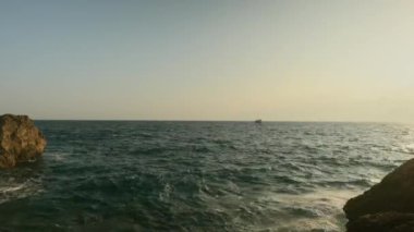 Gün batımında kayalık sahil ve deniz manzarası. Antalya. Tekne denizde yüzüyor. Yüksek kalite 4k görüntü