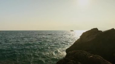 Gün batımında kayalık sahil ve deniz manzarası. Antalya. Tekne denizde yüzüyor. Yüksek kalite 4k görüntü