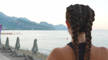 Kız sahile, denize ve dağlara bakıyor. Yüksek kalite 4k görüntü