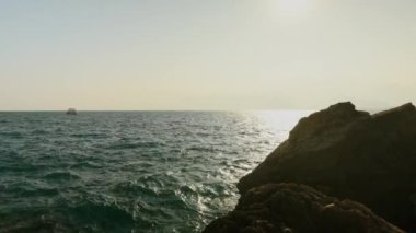 Gün batımında kayalık sahil ve deniz manzarası. Antalya. Tekne denizde yüzüyor. Yüksek kalite 4k görüntü