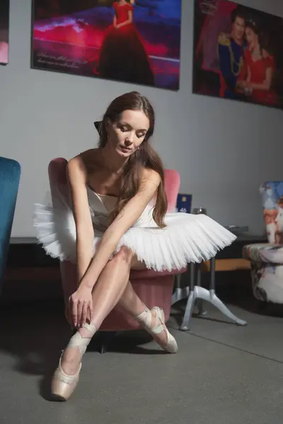 Beyaz etekli ve sivri uçlu ayakkabılı bir balerin sandalyede oturur. Yüksek kalite fotoğraf