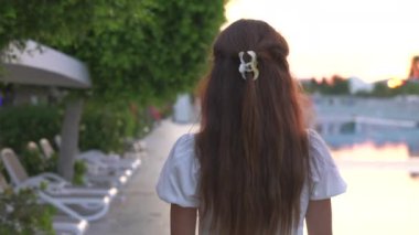 Altın saat boyunca havuzda dolaşan beyaz elbiseli bir kız. Yüksek kalite 4k görüntü