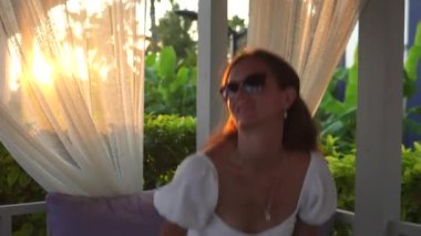 Beyazlı bir kız terasta yürüyor, gözlüklerini ayarlıyor. Yüksek kalite 4k görüntü