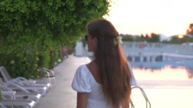 Altın saat boyunca havuzda dolaşan beyaz elbiseli bir kız. Yüksek kalite 4k görüntü