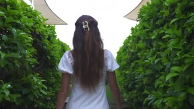 Beyazlı bir kız yeşilliğin içinden denize doğru yürüyor. Yüksek kalite 4k görüntü