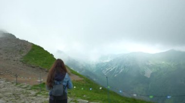 Kasprowy Wierch 'e doğru yürüyen bir kız. Zakopane. Bulutların sisinde panoramik manzara. Yüksek kalite 4k görüntü