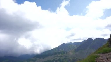 Üstte telefonu olan bir kız. Zakopane, bulutların sisinde panoramik manzara. Yüksek kalite 4k görüntü