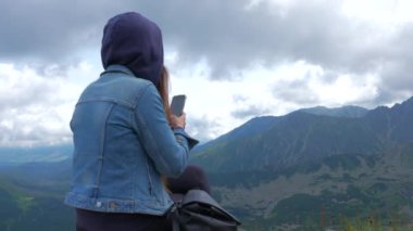 Üstte telefonu olan bir kız. Zakopane, bulutların sisinde panoramik manzara. Yüksek kalite 4k görüntü