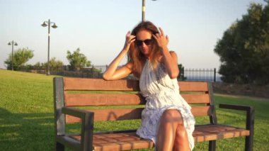 Parktaki bankta oturan bir kız saçıyla oynar ve arkadaşını bekler. Yüksek kalite 4k görüntü