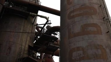Kalabalık bir şehir ortamındaki harap olmuş endüstriyel yapıların ve boruların büyüleyici ve çarpıcı görüntüsü