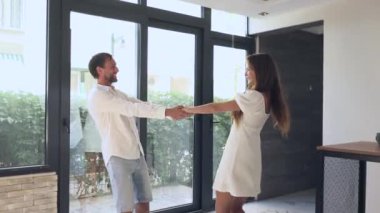 Neşeli bir çift, doğal ışıkla dolu, parlak ve modern bir iç mekanda, keyifli bir dansı mutlulukla paylaşıyor.
