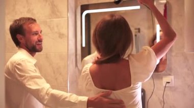 Kocası banyoda dikilirken karısı saçlarını kurutuyor. Aynanın yanında. Birlikte sakin bir sabah rutini uyguluyor. Yüksek kalite 4k görüntü