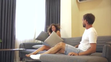 Bir çift sevinçle kanepeye atlar, mutluluktan kahkaha atarlar. Şakacı ve kaygısız bir şekilde minderlerin üzerine yuvarlanırlar, eğlenceli ve spontane bir anı yakalarlar. Yüksek kalite 4k görüntü