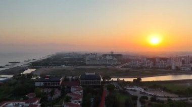 Sakin ve huzurlu bir nehrin yanında modern bir şehir manzarasını aydınlatan nefes kesici bir gün batımı.
