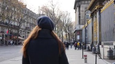 Gri bereli ve ceketli bir kız şehrin ikonik sokaklarında geziniyor, Paris kış zarafetinin özünü yakalıyor.