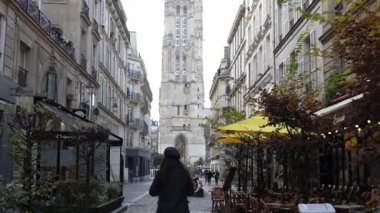 Noel atmosferinde, gri bereli bir kız Saint-Jacques Kulesi 'ne doğru güzel dekore edilmiş bir caddede yürüyor ve şehrin tatil ruhunu yakalıyor..