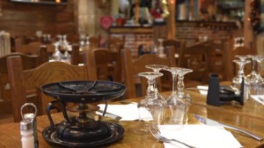 Paris restoranının masası fondü ocakları ve gözlüklerle süslenmiş, bir şenlik dekorasyonuna karşı kurulmuş. Kurulum, rahat bir tatil yemeği deneyimini yakalıyor. 4k görüntü