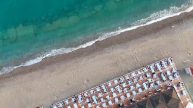 Çarpıcı bir gün batımıyla aydınlatılan deniz kıyısındaki bir restoranın havadan görünüşü suya canlı renkler yansıtıyor ve pitoresk bir yemek atmosferi yaratıyor. Yüksek kalite 4k görüntü