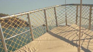 Bir yat denizde süzülüyor, dalgaları yarıp geçiyor. Uzakta yükselen bir kaya oluşumu tarafından çerçevelenen sahne, büyüleyici doğal bir arka plana karşı deniz macerasının güzelliğini yakalar.