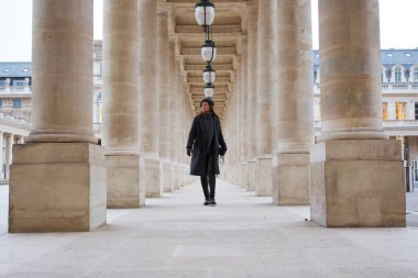 Bere ve kışlık palto giyen Parisli bir kadın, klasik Fransız zarafet ve cazibesini kucaklayarak Palais Royal 'in büyük sütunlu geçidinde yürüyor. Yüksek kalite fotoğraf