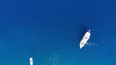 Bu büyüleyici insansız hava aracı açık denizde demirlemiş bir grup beyaz yatı, turistlerin berrak, mavi suların tadını çıkarırken yakalıyor. Kaliteli 4k görüntü
