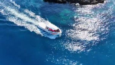 Bu canlı İHA görüntüsü, bereketli bir ada zeminiyle berrak sularda yüzen bir turist teknesini yakalıyor. Kaliteli 4k görüntü