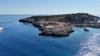 Bu çarpıcı drone görüntüsü, insanların teknelerin etrafındaki kristal berrak turkuaz sularda yüzdüğü tropik bir adanın yakınındaki turistik yatları çekiyor. Kaliteli 4k görüntü