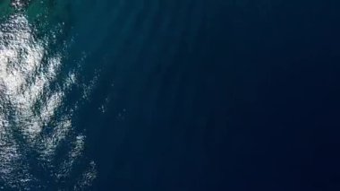 Geniş mavi denizin üzerinde dinamik bir dron atışı başlıyor, engebeli, kayalık bir adayı düzgün bir şekilde ortaya çıkarmadan önce sakin suları yakalıyor. Yüksek kalite 4k görüntü