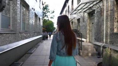 Bir kız Lodz 'da yürür aynalı sokakta, altın güneş ışığıyla yıkanır. Yansıtıcı duvarlar göz kamaştırıcı desenler sergiliyor, gerçeküstü ve canlı bir şehir manzarası yaratıyor.