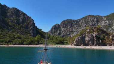 Bu çarpıcı hava görüntüsü Antalya kıyı şeridinin nefes kesici güzelliğini yakalar. Dramatik kayalık dağların çerçevelediği el değmemiş sahil güneş ve suyun keyfini çıkaran insanlarla dolu..