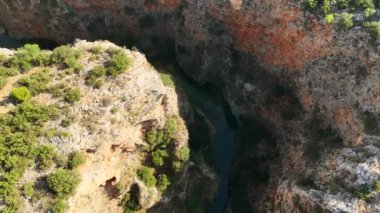 Parlak, güneşli bir günde Kapuz Kanyonu 'nun göz alıcı kuşları engebeli kanyondan akan canlı turkuaz suları yakalıyor. Huzurlu sahne insanlardan yoksun.