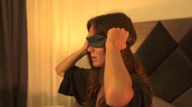 Sıcak bir yatak odası ortamında huzurlu bir geceye hazırlanırken göz maskesi takan bir kadının yakın plan fotoğrafı.. 