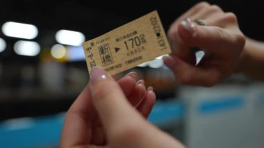 Tokyo metro biletini elinde tutan kadınların yakın plan görüntüsü, seyahat, toplu taşıma ve Japon kentsel yaşam tarzını temsil ediyor.. 