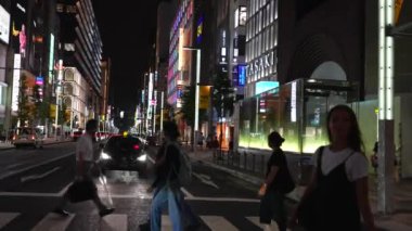 11 Ekim 2023 'te Tokyo, Japonya' daki yaya geçidinde kalabalık, dükkanlar ve hareketli şehir atmosferiyle hareketli bir akşam sahnesi.. 