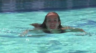 Havuzda yüzen, neşe ve rahatlıkla gülümseyen, açık havada mutlu bir yaz anını yakalayan güzel bir kızın yakın çekimi.. 