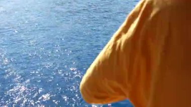 Hareket halindeki bir yatta bir balıkçı oltayla bir balığı sudan çekip açık denizde hareketli ve heyecan verici bir manzara yakalar..