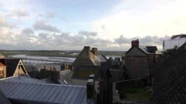 Fransa 'nın Mont-Saint-Michel Abbey kentindeki antik binaların cephelerini yansıtan panoramik bir manzara, ayrıntılı ortaçağ mimarisi ve tarihsel önemi gözler önüne seriyor..