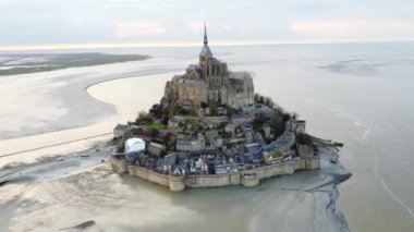 Tarihi Mont Saint-Michel 'i ve etrafındaki geniş gelgit düzlüklerini gösteren hava manzarası, kıyı güzelliğini vurguluyor..