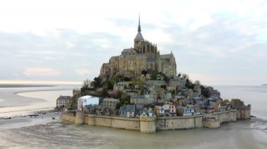 Mont Saint-Michel Manastırı ve ortaçağ köyü Normandiya 'da gün batımının sıcacık parıltısıyla aydınlanarak nefes kesici bir manzara yarattı..