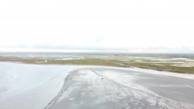 Mont Saint-Michel yakınlarındaki gelgit düzlüklerini keşfeden ziyaretçiler, çarpıcı doğal manzarayı ve bölgenin tarihi atmosferini gözler önüne seriyorlar..